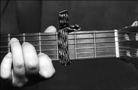 Un capo en el cuello de la guitarra. Observe que el capo se encuentra justo antes del traste - no directamente en t